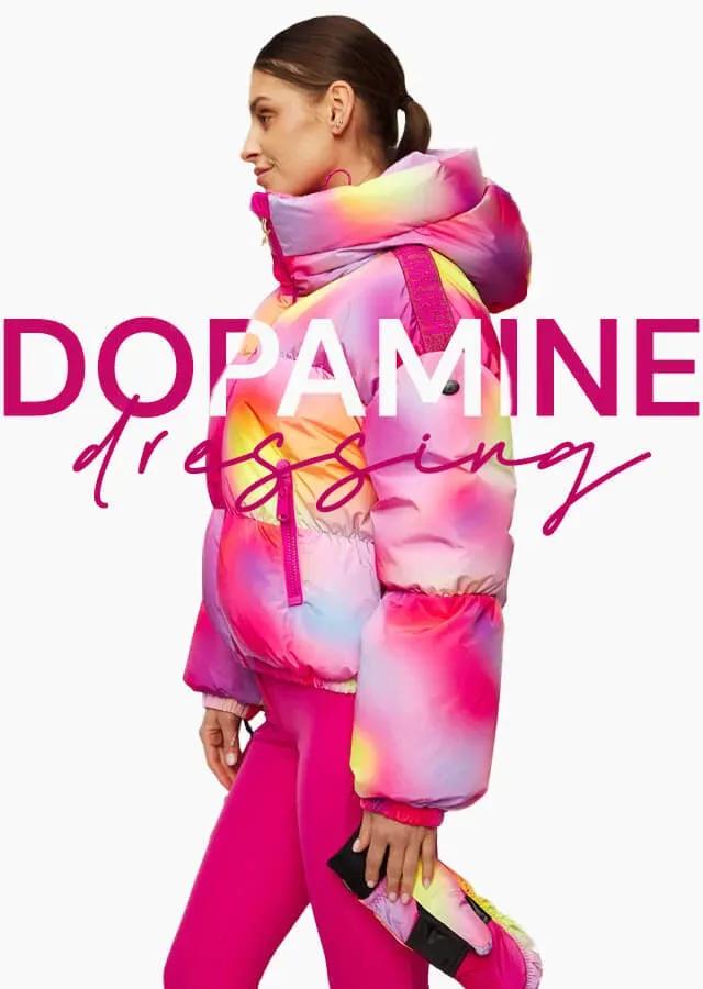 Femme en veste rose et jaune à la mode pour les pistes de ski