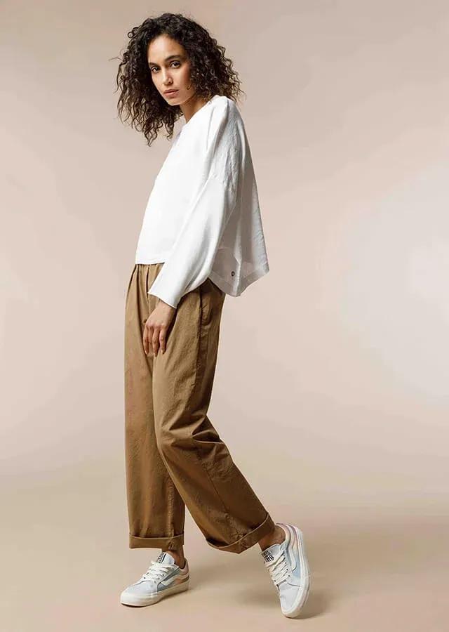 femme en pantalon marron et pull blanc