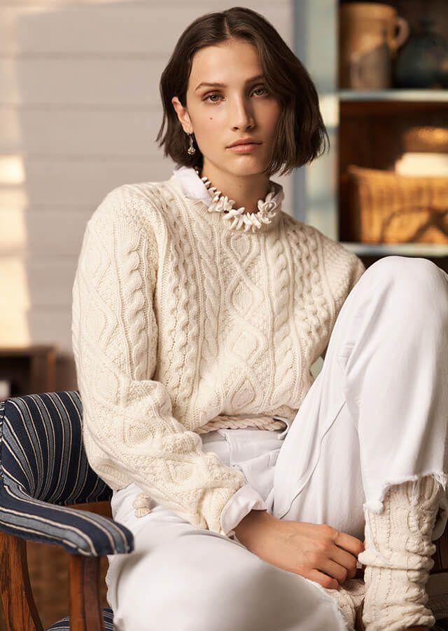 Standing woman in white jumper and white trousers styled in the 1940s