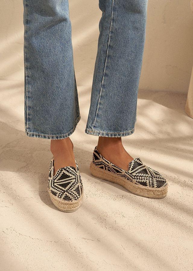 Woman's legs in fashionable summer espadrilles and bright jeans