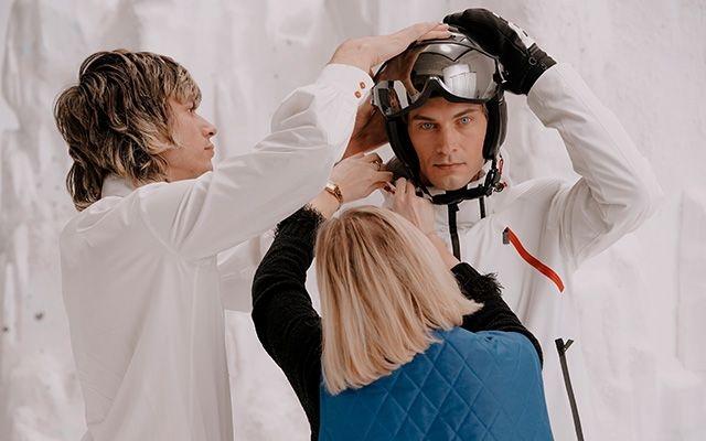 Woman and man helping another man fasten his helmet