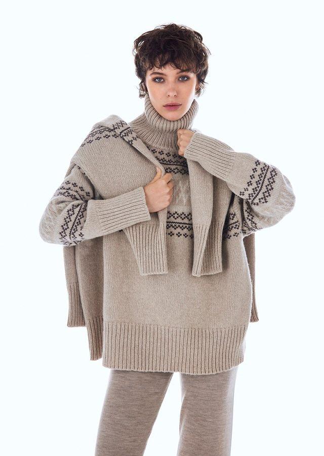 Femme debout portant un pull en laine mérinos beige à motif norvégien