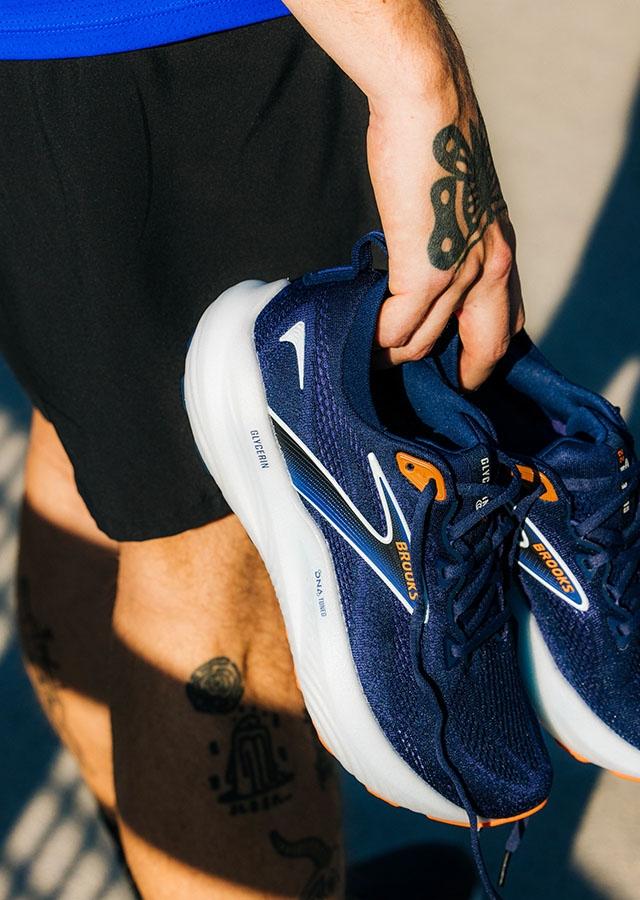 Mężczyzna trzymający w ręce buty biegowe Brooks 