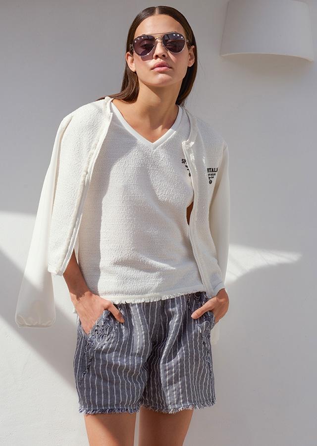 Kobieta w białym T-shircie, okularach przeciwsłonecznych i niebieskich szortach z paskami w stylu casual  