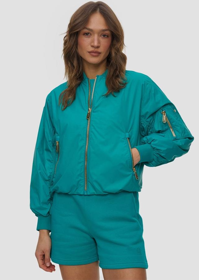 Kobieta w zielonym komplecie od marki Goldbergh idealnym na city break 