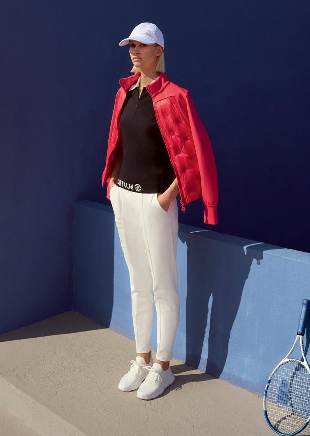 Moda sportowa 2026 – kobieta w czerwonej kurtce i białych spodniach 