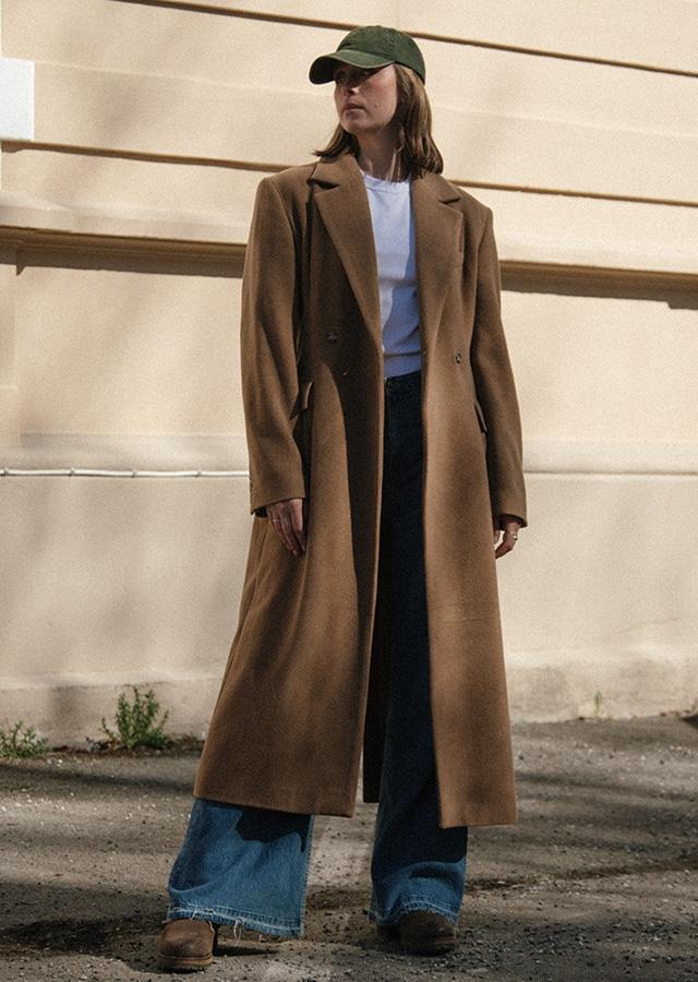 Kobieta w długim, brązowym płaszczu i szerokich jeansach
