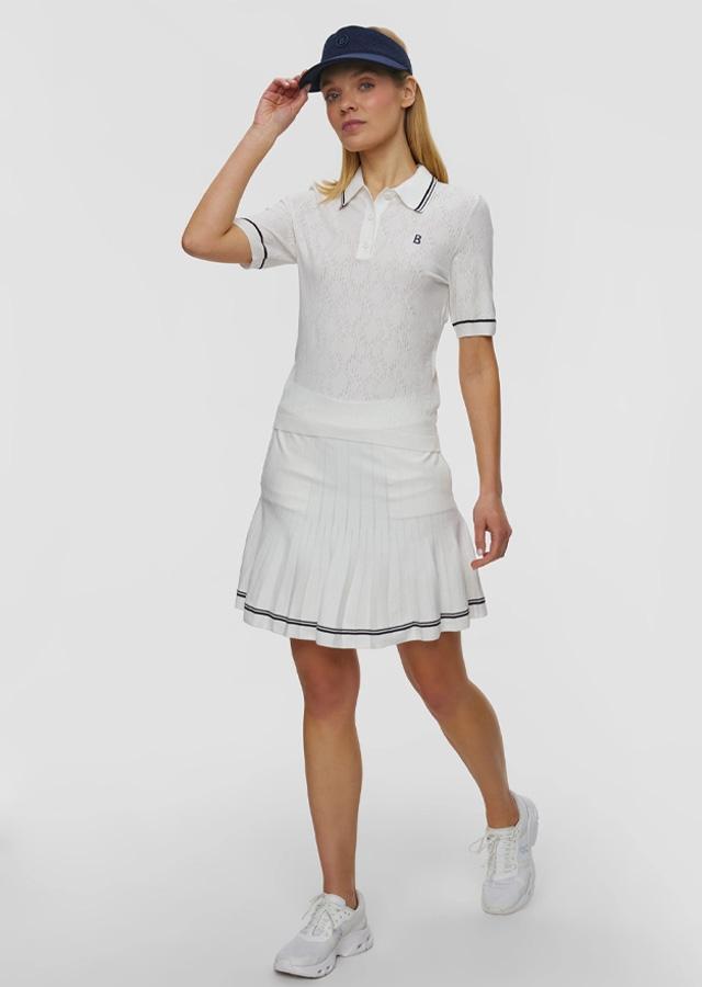 Kobieta w białej plisowanej spódniczce i charakterystycznej koszulce polo Kobieta w białej plisowanej spódniczce i charakterystycznej koszulce polo