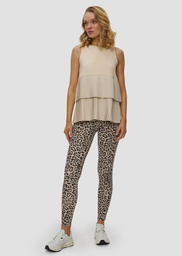 Kobieta w legginsach w panterkę i beżowym topie z falbanką Kobieta w legginsach w panterkę i beżowym topie z falbanką